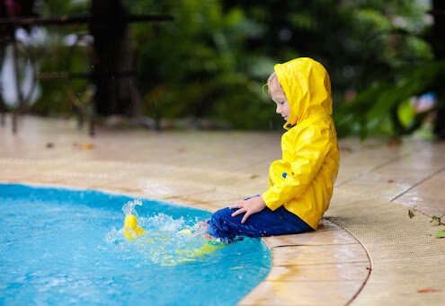 kid in a raid coat by the pool after a storm