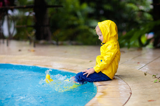 kid in a raid coat by the pool after a storm